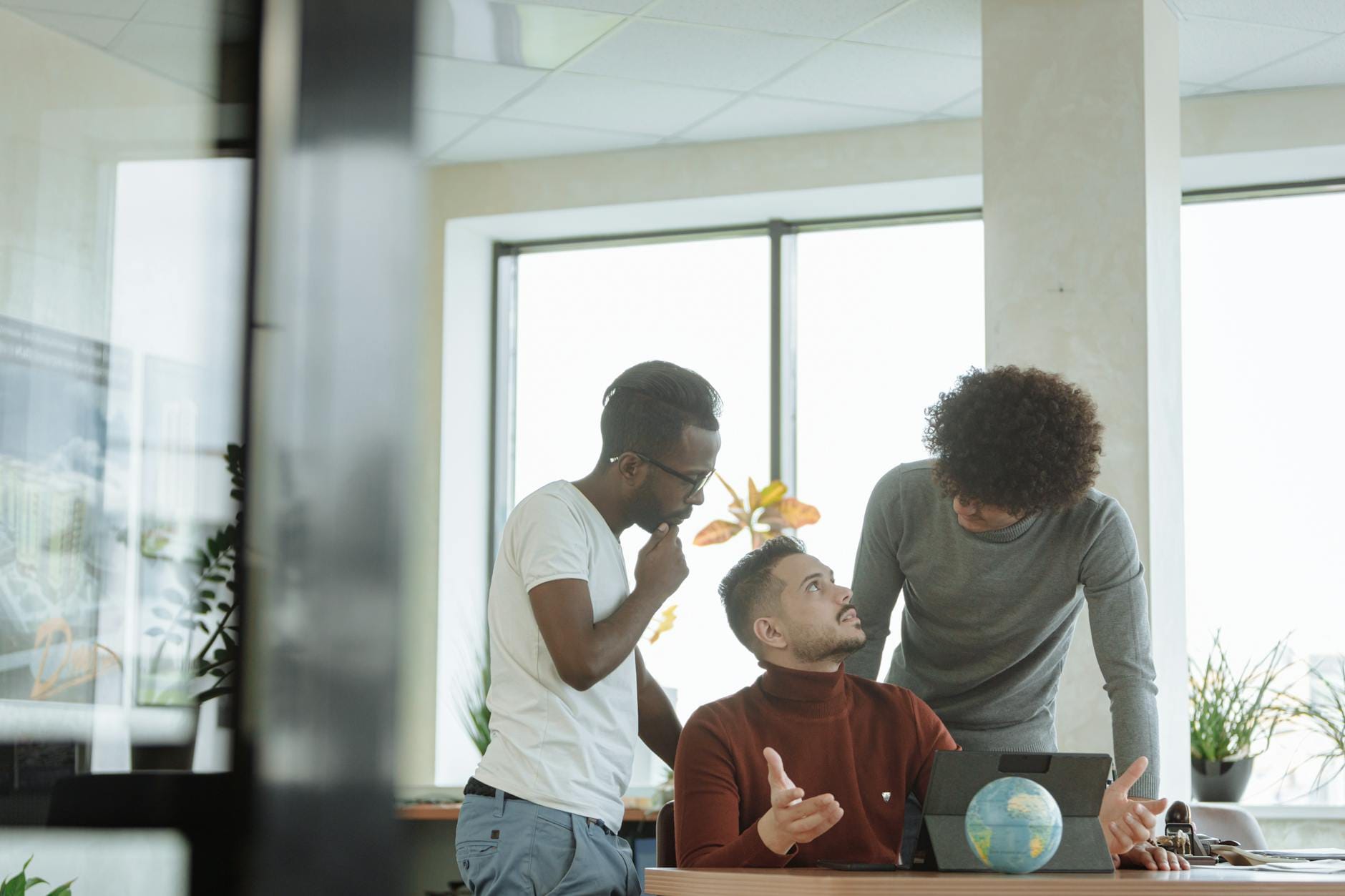 A diverse group of male colleagues discussing strategies in a modern office setting.