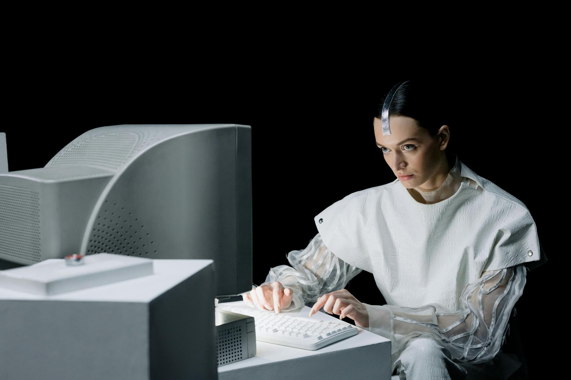 A woman in a futuristic setting working on an old computer, suggesting a blend of past and future.