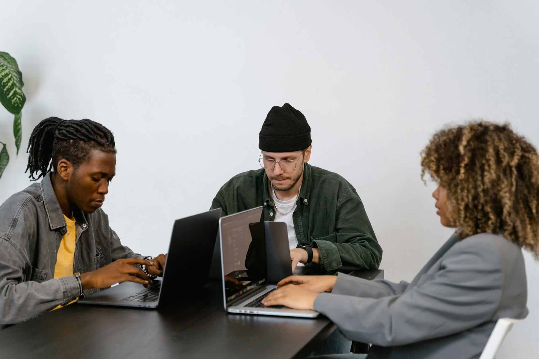 A diverse group of professionals working together on laptops in a contemporary office environment.