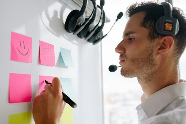 Focused businessman writing on sticky notes attached to a whiteboard during a meeting.