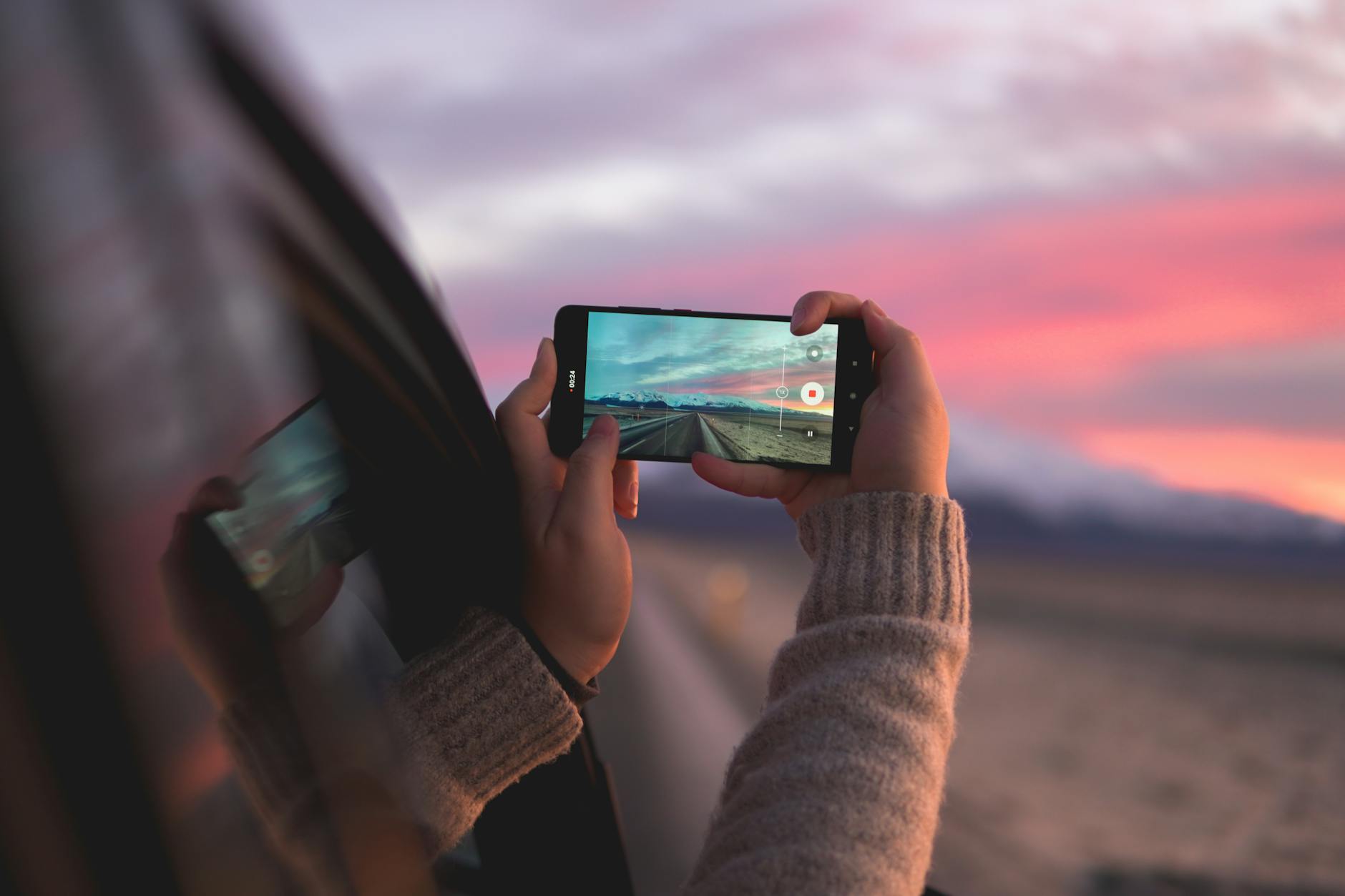 A person captures a stunning Icelandic sunset through a smartphone while traveling.