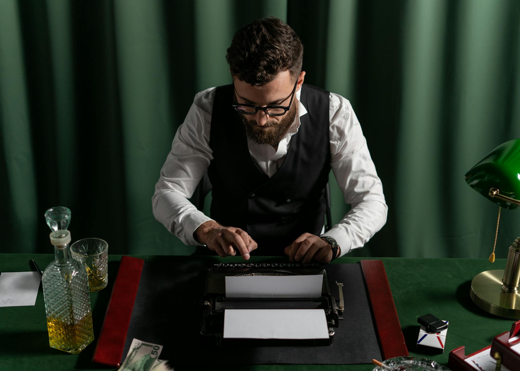 Man in a vintage office typing on a typewriter with a focused expression under warm lighting.
