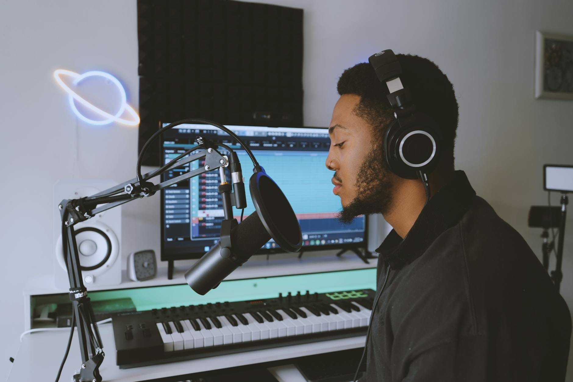 A musician recording vocals in a modern home studio setup with professional audio equipment.