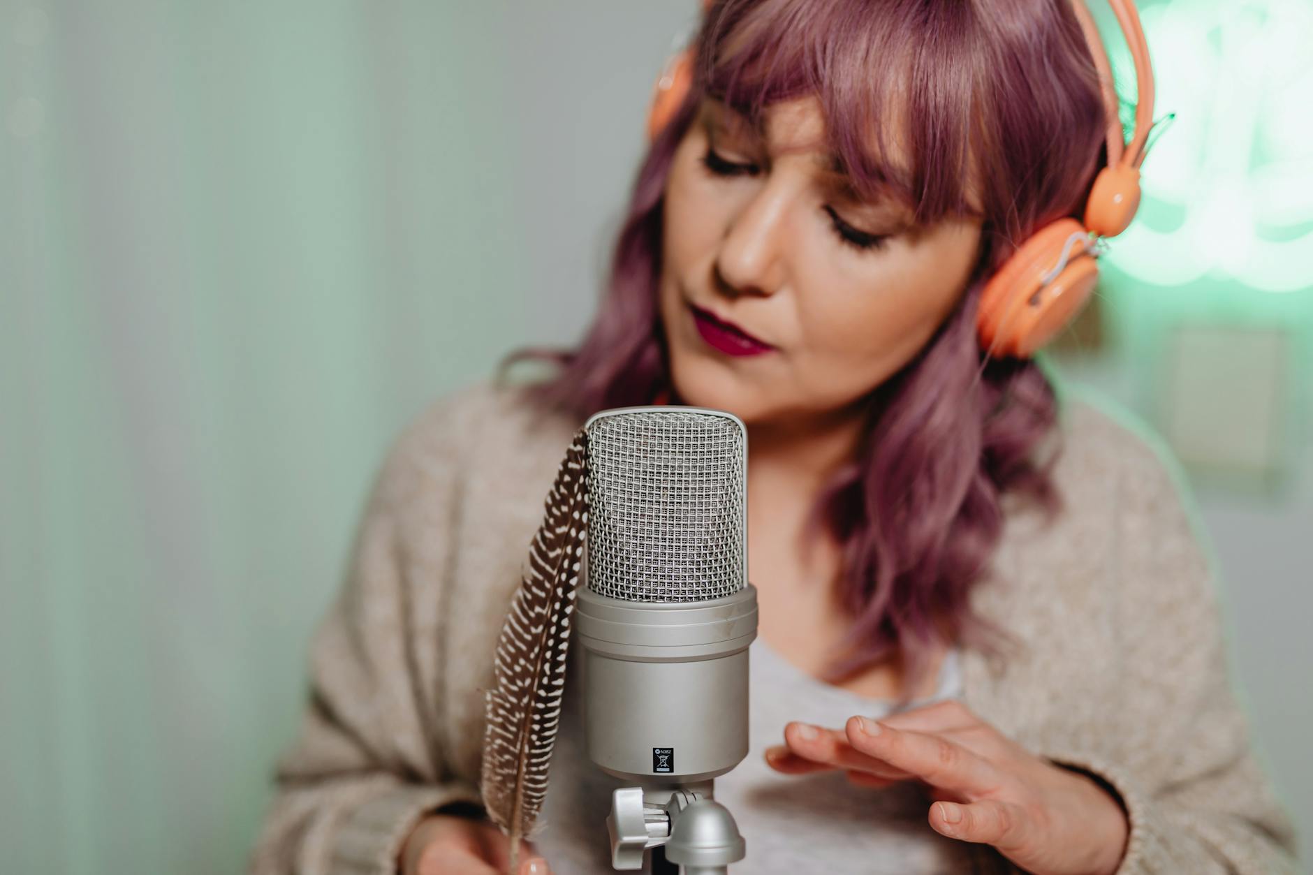 Close-up of ASMR artist with microphone, feather, and headphones.
