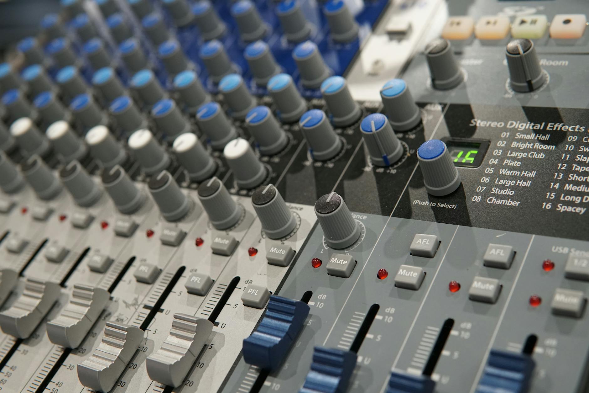Detailed view of a modern audio mixing console with knobs and faders for sound engineering.