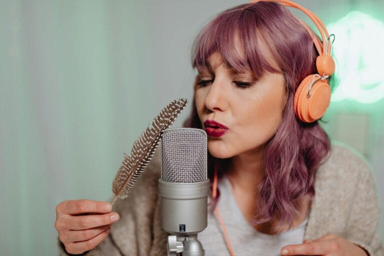 Caucasian woman using a feather to create ASMR sounds with a microphone indoors.