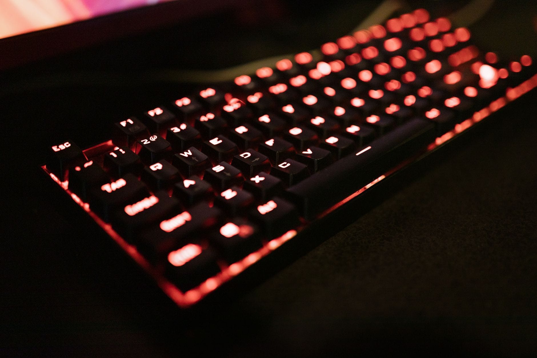 Close-up of an illuminated mechanical keyboard with red LED backlighting, perfect for gaming enthusiasts. — brave search