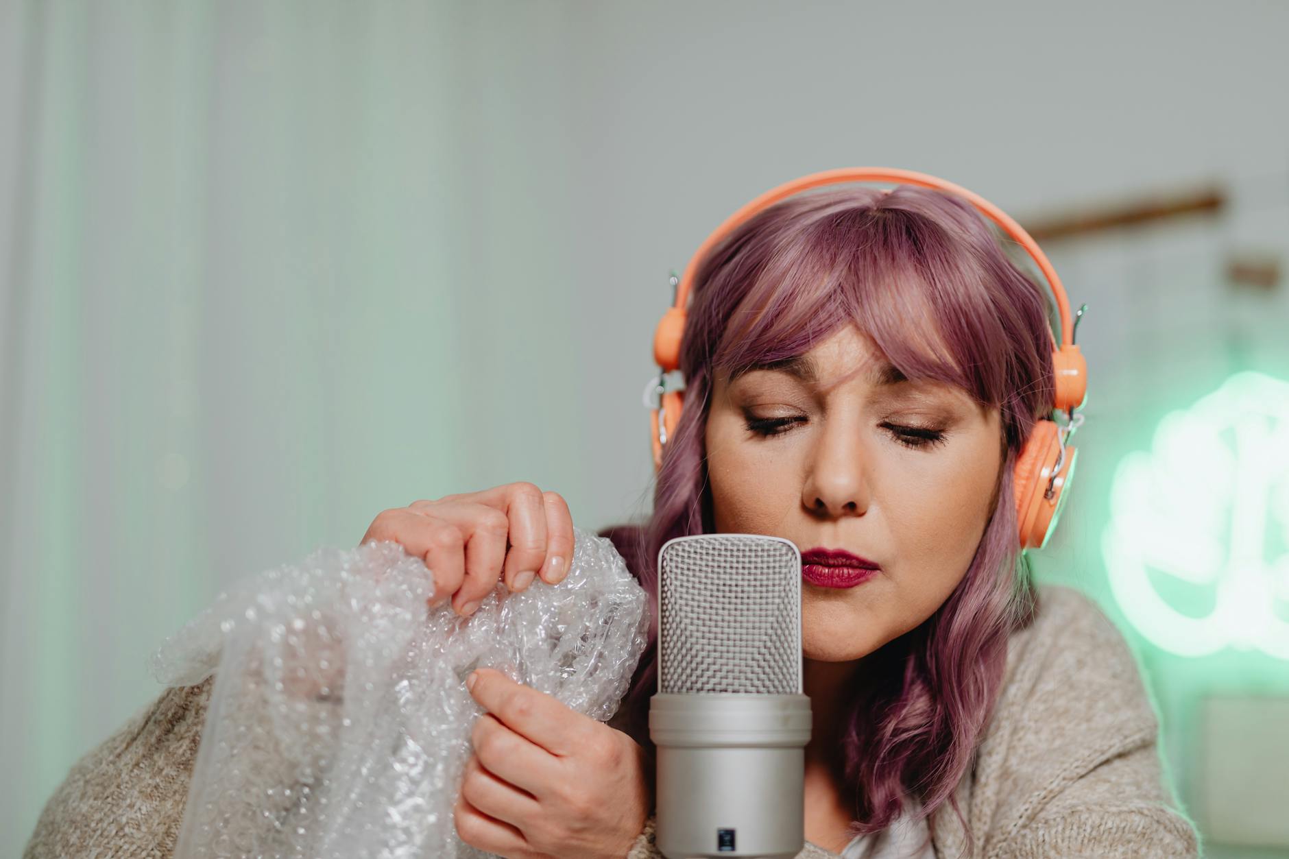 A woman with purple hair performs ASMR using bubble wrap and a microphone. — elevenlabs music app ai music generation 20