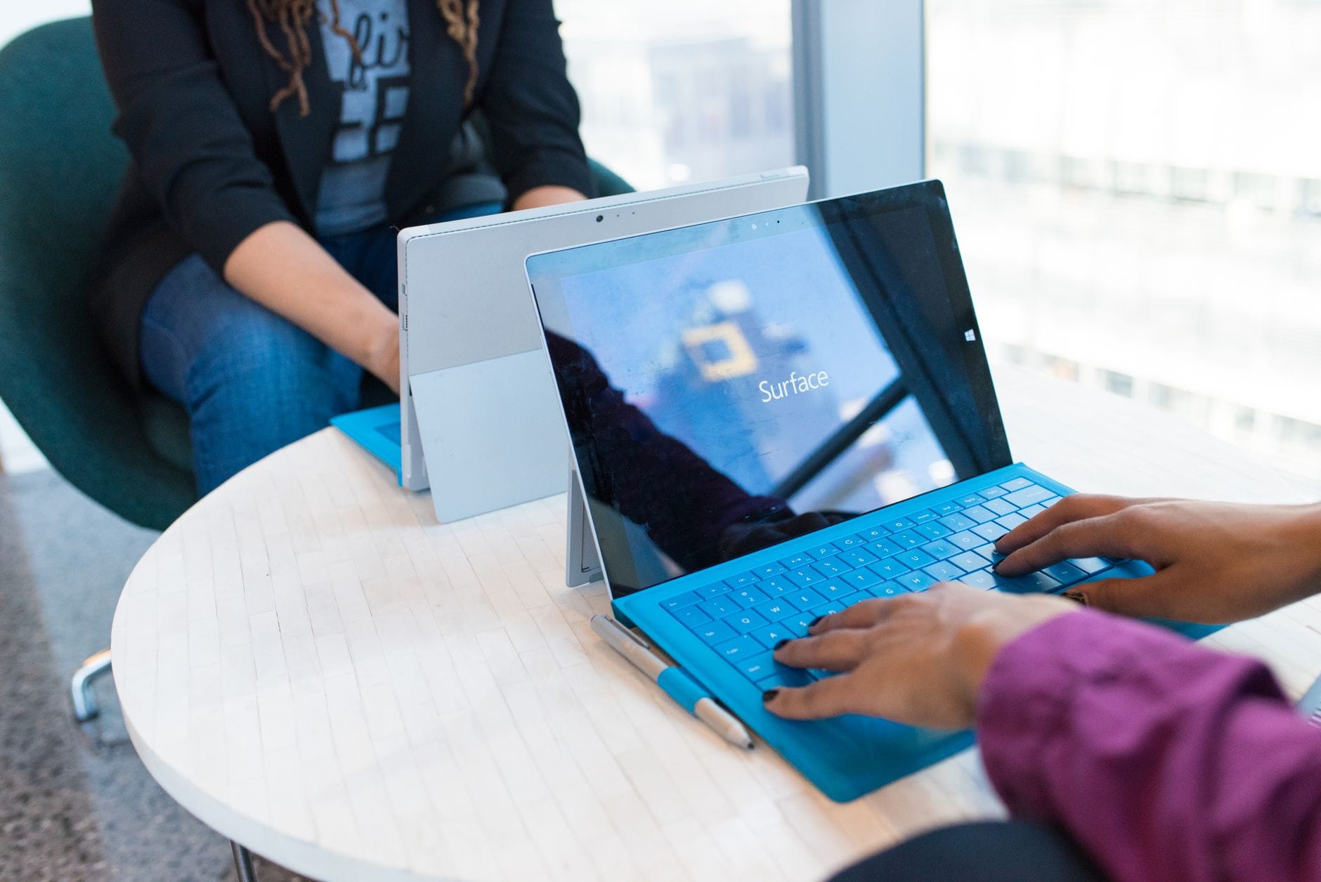 Two people using modern laptops in a bright office setting, showcasing technology in use. — best ai meeting tools 2026