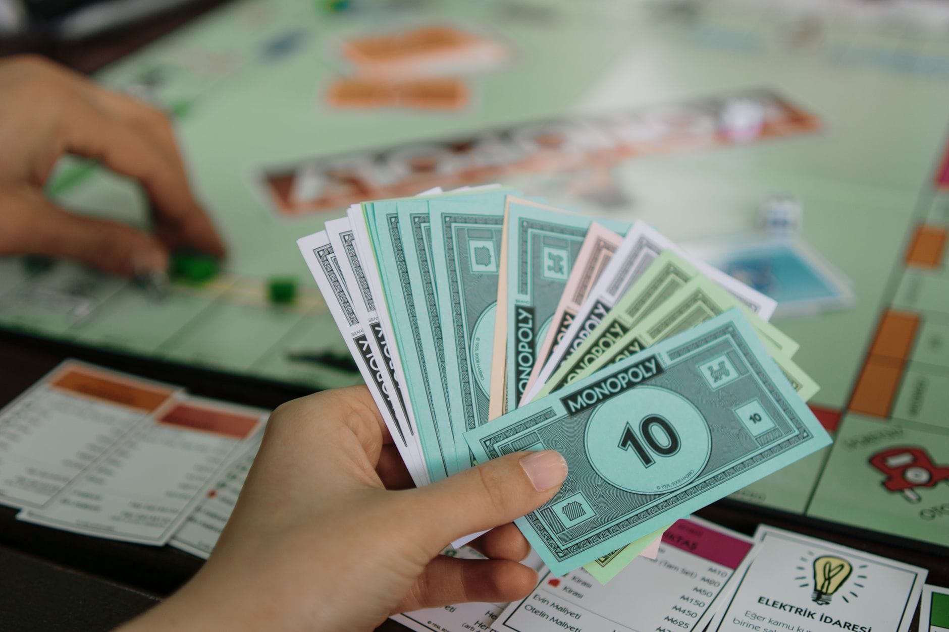 A close-up view of a person holding Monopoly money while playing the board game. — hubspot review 2026