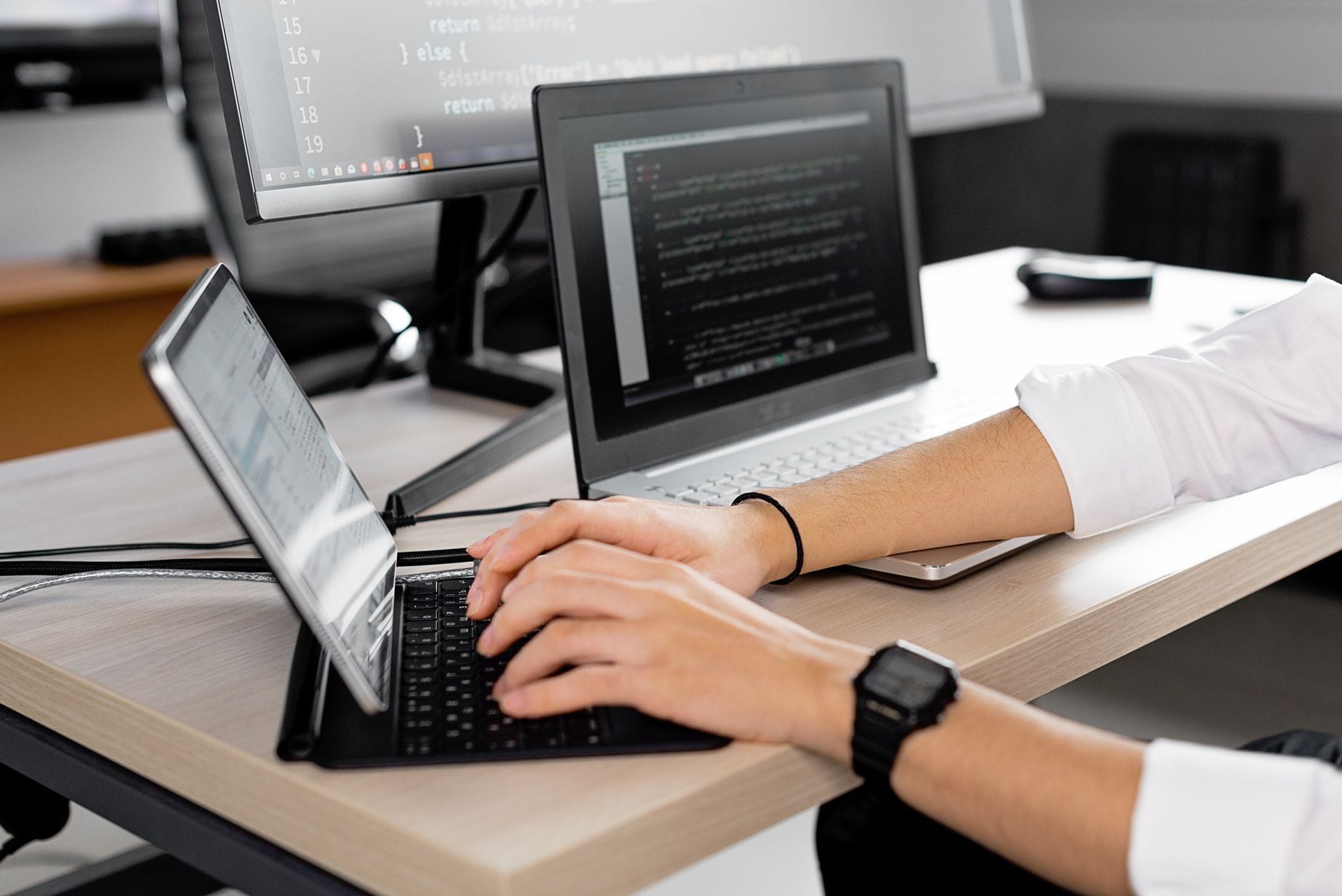 Candid shot of a programmer at work using multiple screens to code in a modern office. — cursor review 2026