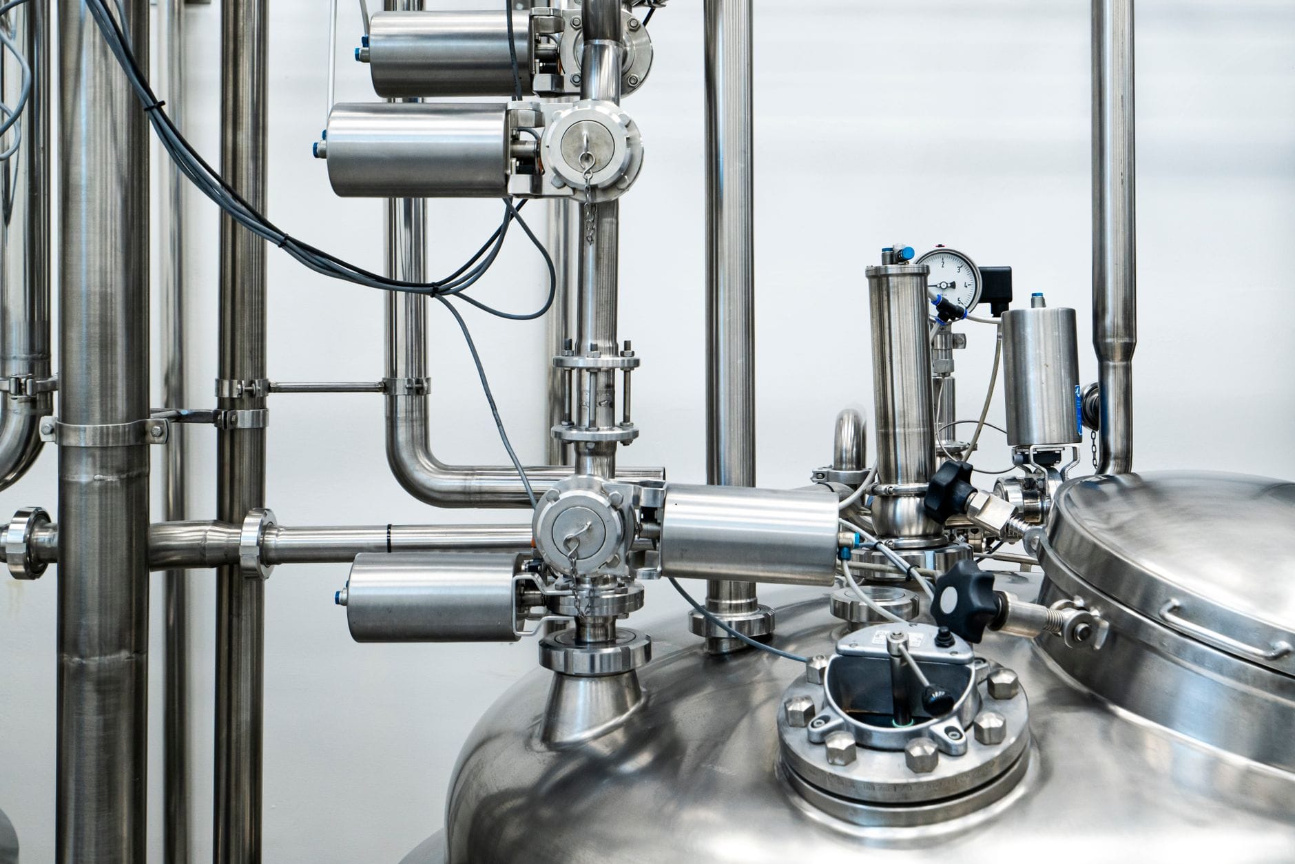 Close-up of stainless steel machinery and pipes in an industrial setting, showcasing modern engineering. — claude mania