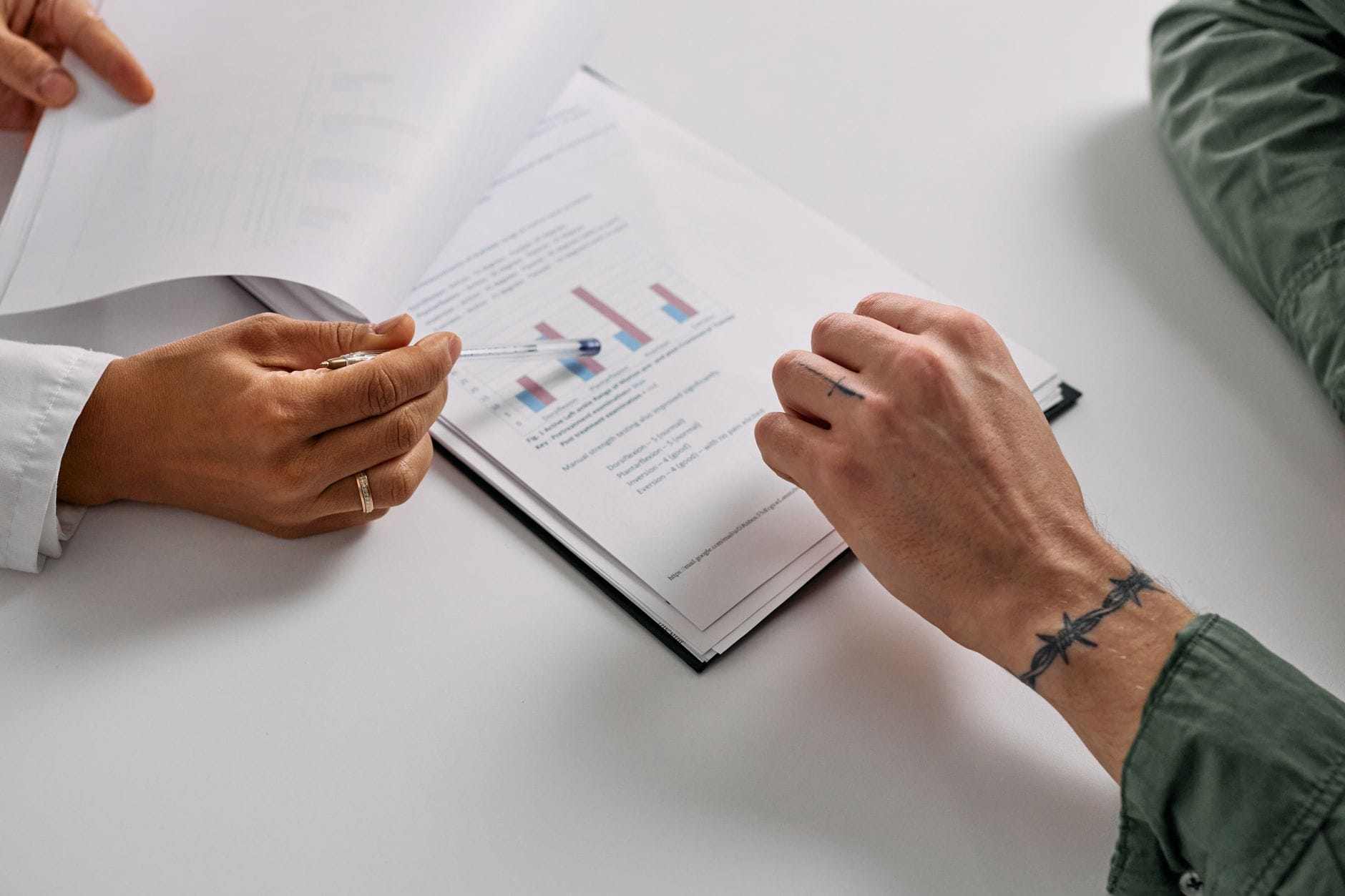 Close-up of hands reviewing documents with graphs, emphasizing teamwork and analysis. — openai cybersecurity model stagg