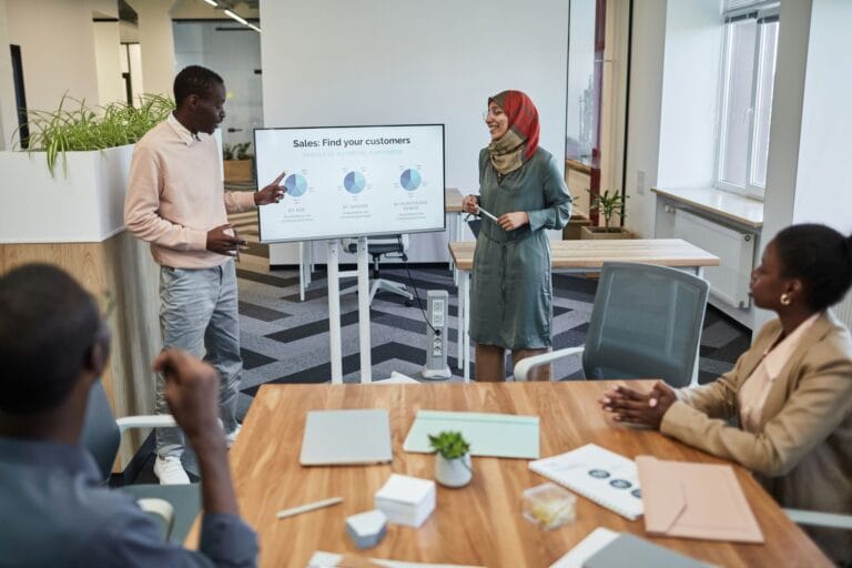 A diverse team engaging in a business meeting focused on sales strategy with visual aids. — forbes ai 50 list 2026 top c