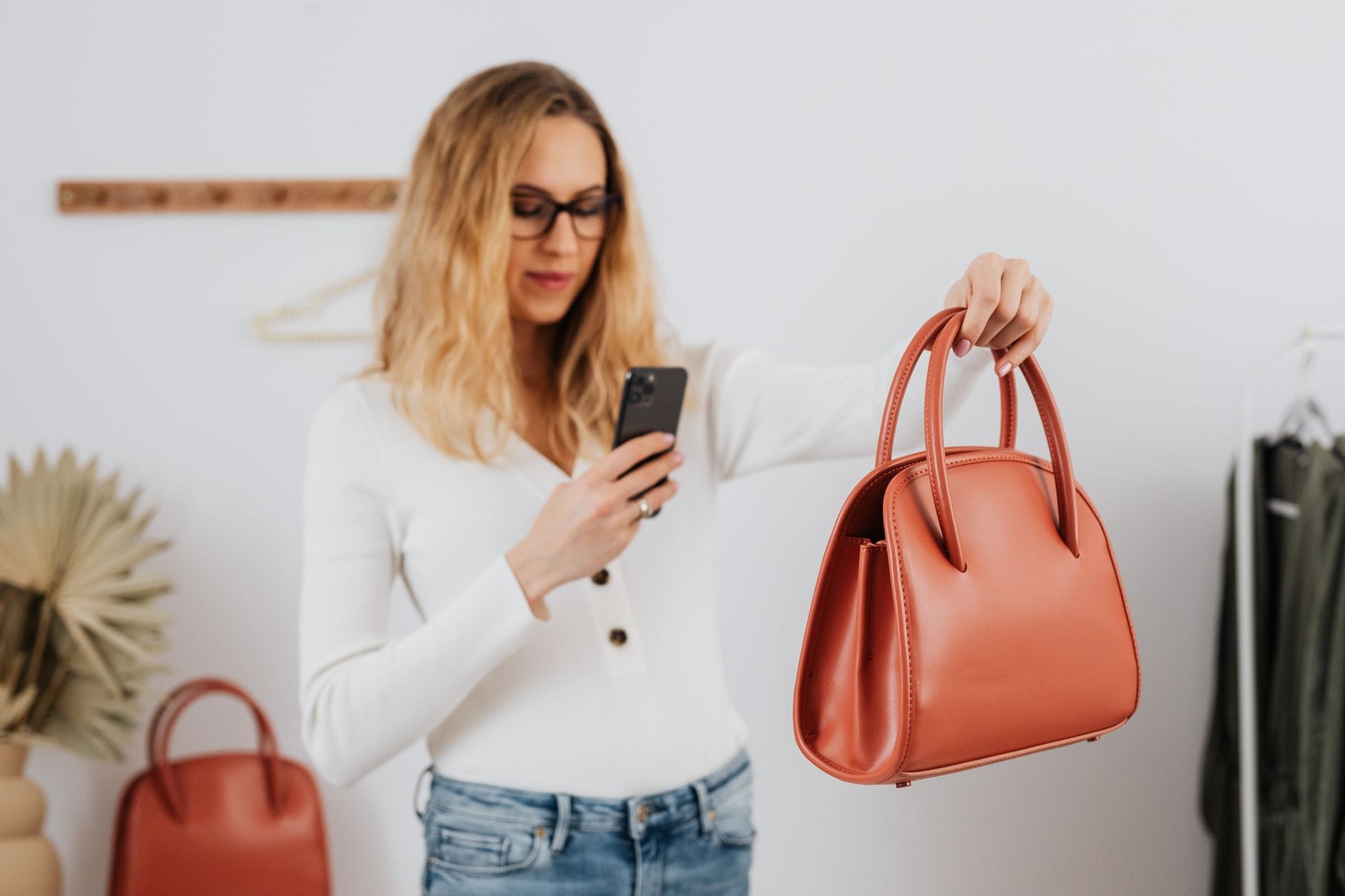 A woman photographs a stylish leather handbag with her smartphone for online selling. — forbes ai 50 list 2026 top compa
