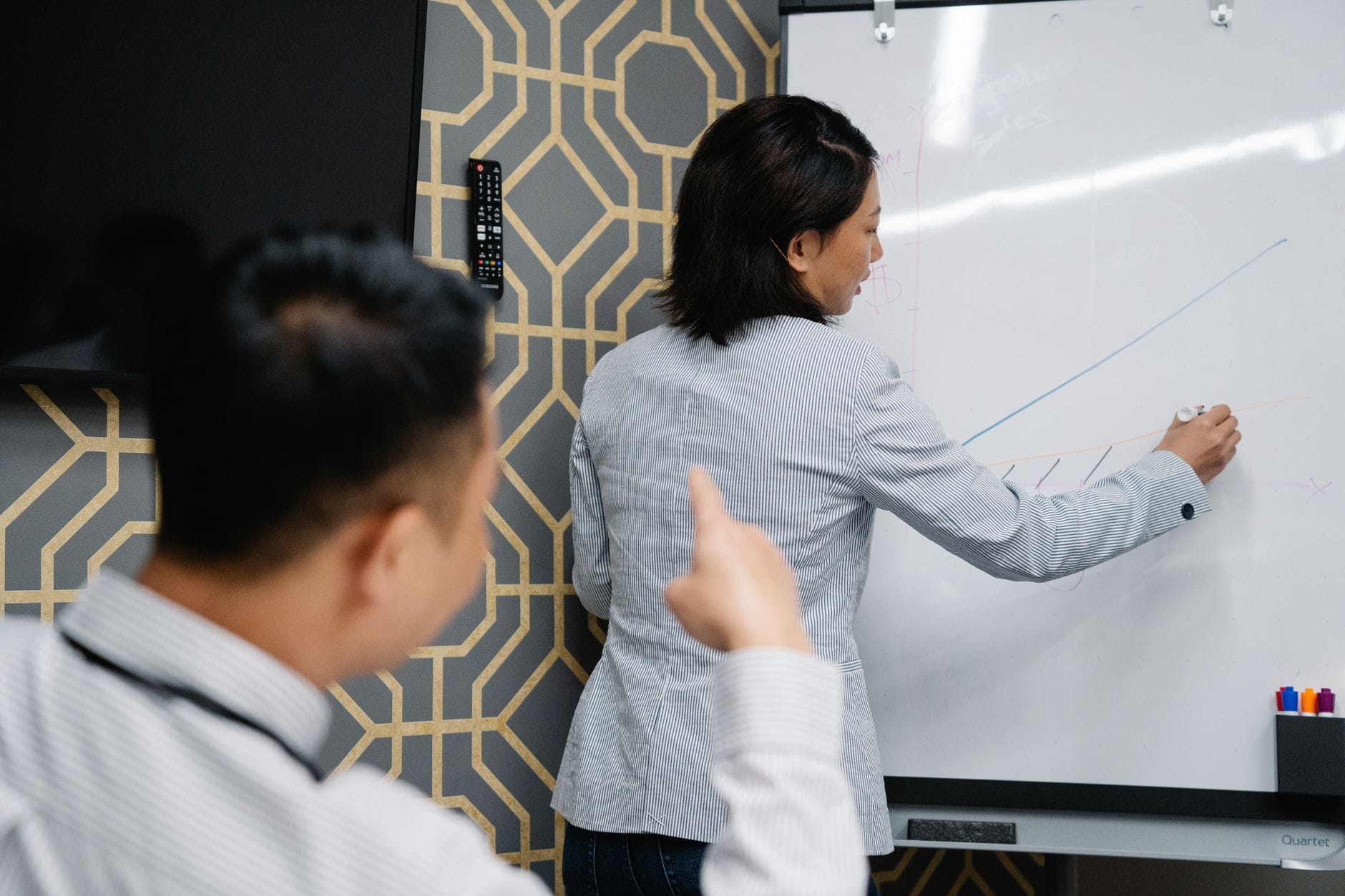 Two professionals in an office discussing a graph on a whiteboard during a business presentation. — openai super app cod