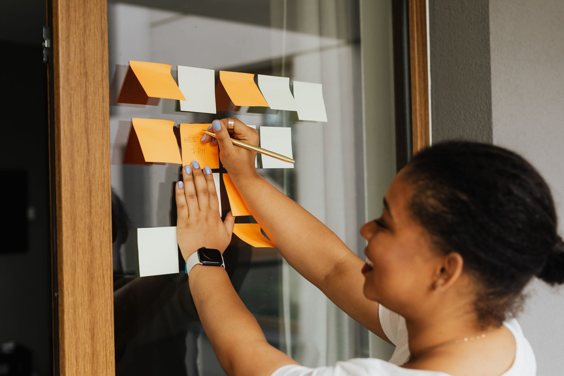 A woman writes notes on a window using colorful sticky notes, emphasizing planning and creativity. — linear mcp server m